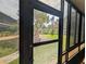 The enclosed patio has dark framed windows surrounding the perimeter with views of green grass and palm trees at 190 Hickory Woods Ct # 15C, Deltona, FL 32725