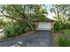 A paved driveway leads to a two-car garage bordered by mature trees and shrubs at 2149 Hontoon Rd, Deland, FL 32720