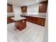 Kitchen with tile floors, granite countertops, wood cabinets, and an island for extra prep space at 2301 Angel Fish Loop, Leesburg, FL 34748