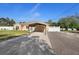 Long driveway leading to a tan home with a matching carport and white fence, under a clear blue sky at 2530 Leonard Dr, Deltona, FL 32725