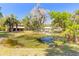 Scenic view of a pond with lush landscaping and a charming barn-style house in the background at 2646 Turnbull Bay Rd, New Smyrna Beach, FL 32168