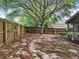 A vast backyard with a large tree, surrounded by a wooden fence and some greenery at 30029 Pga Dr, Sorrento, FL 32776