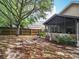 Backyard featuring a screened patio with outdoor seating, complemented by a wooden fence and mature trees at 30029 Pga Dr, Sorrento, FL 32776