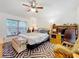 This bedroom features a ceiling fan, large window, and patterned carpet at 30029 Pga Dr, Sorrento, FL 32776
