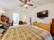 This bedroom is filled with natural light and has a ceiling fan and television at 30029 Pga Dr, Sorrento, FL 32776