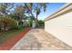 This brick-paved backyard patio, adjacent to the home, offers a serene outdoor space, bordered by lush greenery and shade trees at 3005 Garden Rd, Eustis, FL 32726