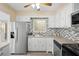 Well-lit kitchen featuring stainless steel refrigerator, mosaic tile backsplash, and white cabinetry at 3005 Garden Rd, Eustis, FL 32726