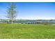 Picturesque lake view featuring a wooden dock, grassy lawn, and clear blue sky at 3005 Garden Rd, Eustis, FL 32726