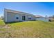 View of the backyard featuring a well-maintained lawn and a home exterior with a sliding glass door and windows at 303 Puffer Ct, Kissimmee, FL 34759