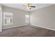 A carpeted room featuring neutral walls and a ceiling fan, bathed in natural light from two windows at 303 Puffer Ct, Kissimmee, FL 34759