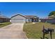 Charming single-Gathering home featuring a well-manicured lawn, a two-car garage, and a classic gray exterior at 303 Puffer Ct, Kissimmee, FL 34759