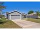 View of a gray home with a large driveway leading to an attached two-car garage at 303 Puffer Ct, Kissimmee, FL 34759