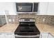 Close up of stainless steel oven and stovetop featuring granite countertops and decorative backsplash at 303 Puffer Ct, Kissimmee, FL 34759