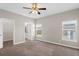 Main bedroom with two windows, neutral walls, carpet flooring, ceiling fan, and a view to the ensuite bathroom at 303 Puffer Ct, Kissimmee, FL 34759