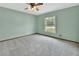 Bright bedroom features soft carpet, ceiling fan, and a window with views at 3041 Millstone Ave, Deltona, FL 32738