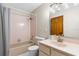 Bathroom featuring pink tile in shower and vanity with tub and a square mirror with globe lighting above at 3104 Umbrella Tree Dr, Edgewater, FL 32141
