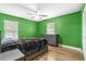Bedroom features green walls, wood floor, and a gray dresser set against a window at 3104 Umbrella Tree Dr, Edgewater, FL 32141