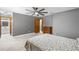 Gray bedroom featuring a ceiling fan, carpet, and view of bathroom through an open, wood door at 3104 Umbrella Tree Dr, Edgewater, FL 32141