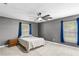 Spacious bedroom features neutral carpet, two windows, a ceiling fan, and bedside tables at 3104 Umbrella Tree Dr, Edgewater, FL 32141