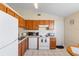 Kitchen featuring wooden cabinets, white appliances, and tile flooring for a cozy cooking space at 3237 Cranston St, Deltona, FL 32738