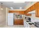 Functional kitchen featuring white appliances, wood cabinets, and well-lit tile floors at 3237 Cranston St, Deltona, FL 32738