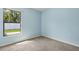 Light blue bedroom featuring carpeted floors and a window overlooking a yard at 3845 Arborvitae Way, Deland, FL 32724