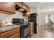 Galley kitchen featuring wood cabinets, granite countertops, and black appliances at 3845 Arborvitae Way, Deland, FL 32724