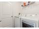 Convenient laundry room features a washer, dryer, overhead shelving, and a white painted door at 3845 Arborvitae Way, Deland, FL 32724