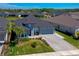 Aerial view of a well-maintained home with a gray exterior, paver driveway, lush lawn, and beautifully landscaped surroundings at 418 Aquamarine Way, Daytona Beach, FL 32124