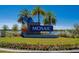 Attractive community entrance sign surrounded by palm trees, colorful landscaping, and a serene lake view at 418 Aquamarine Way, Daytona Beach, FL 32124