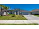 Charming single-story home featuring a well-manicured lawn, palm tree, and paver driveway, presenting excellent curb appeal at 418 Aquamarine Way, Daytona Beach, FL 32124
