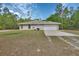 View of the home's side, highlighting the attached garage and simple architecture against a natural backdrop at 4600 S Tomoka Dr, De Leon Springs, FL 32130