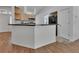 Kitchen with black countertops and bar top, wood flooring, and stainless appliances at 4600 S Tomoka Dr, De Leon Springs, FL 32130