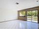 Bright living room featuring white tile flooring, sliding glass door to deck, and large windows overlooking outdoors at 509 Lake Bridge Dr, Ormond Beach, FL 32174