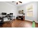 This home office offers wood floors, a ceiling fan, television, and a desk at 5808 Oak Lake Trl, Oviedo, FL 32765