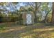 Rustic backyard shed featuring double doors in the grassy, tree-lined yard at 782 Valencia Ave, Orange City, FL 32763