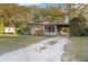 The house features an extended carport and a gravel driveway surrounded by mature trees at 782 Valencia Ave, Orange City, FL 32763