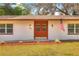 Close up of the front entrance with rich wood double doors, small porch, manicured lawn, and American flag at 816 Overhill Rd, Deland, FL 32720
