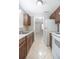 Galley kitchen with stained wood cabinets, white appliances, tile floors, and a view into the next room at 954 Chippendale St, Deltona, FL 32725
