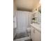 Bathroom features a shower with a white curtain, white shelving unit and white tile floor at 120 Hibiscus Woods Ct # 2A, Deltona, FL 32725