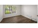 This empty room features wood floors, white trim, and a large window overlooking the front yard at 1253 Bramley Ln, Deland, FL 32720