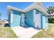 Side view of a teal home with a concrete patio and a white door with stairs at 130 Harrison Rd, Daytona Beach, FL 32118