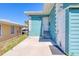 The teal exterior of the home includes a white door and stairs on a concrete patio at 130 Harrison Rd, Daytona Beach, FL 32118