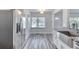 Bright kitchen nook has a large stainless fridge, big window, granite countertop, and gray wood floors at 130 Harrison Rd, Daytona Beach, FL 32118