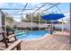 Inviting screened-in pool area with brick patio, water feature, blue umbrellas, and comfortable lounge seating for relaxation at 13944 Huntwick Dr, Orlando, FL 32837