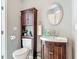 Bathroom featuring a vanity with dark wood cabinetry, a sink, a toilet with storage, and a round mirror at 1578 Stone Trl, Deltona, FL 32725