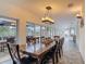 Elegant dining room featuring a long wooden table, modern lighting, and views of the outdoor pool area at 1578 Stone Trl, Deltona, FL 32725