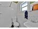 Classic white tiled bathroom featuring a toilet, sink, and overhead shower at 1941 Jungle Rd, New Smyrna Beach, FL 32168