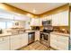 Galley kitchen with stainless steel appliances, white cabinets, and ample counter space and an opening view to the dining area at 2309 6Th Ave, Deland, FL 32724