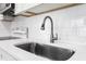 Close up of the kitchen sink showcasing stainless steel fixtures, modern countertops, and bright white backsplash at 2524 Anastasia Dr, South Daytona, FL 32119